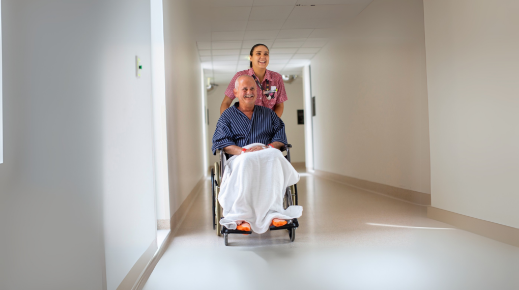 ACL patient in wheelchair with nurse banner