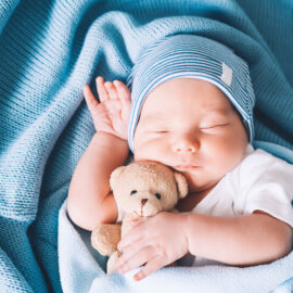 Newborn baby sleep holding a small teddy bear